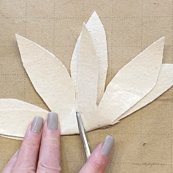 Cutting the center of a fabric flower petal with scissors.