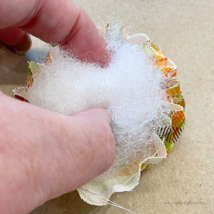 Adding a small bit of polyfil stuffing to the center of a fabric flower.