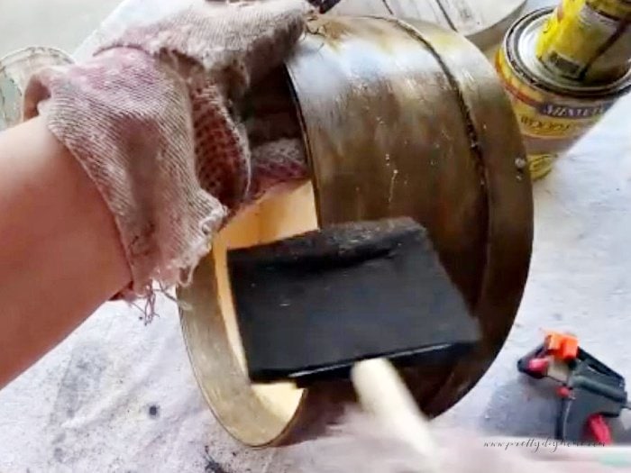 The side of a cheese box being stained with a wide sponge brush.  