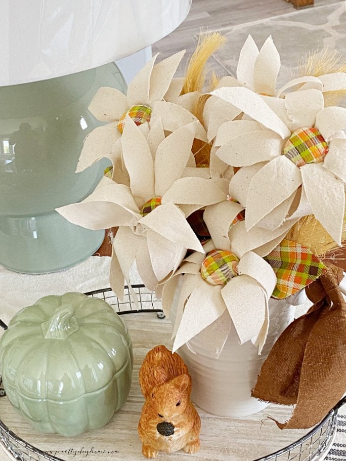 A close up of a bouquet with fabric flowers in cream with orange plaid center for Fall decor.