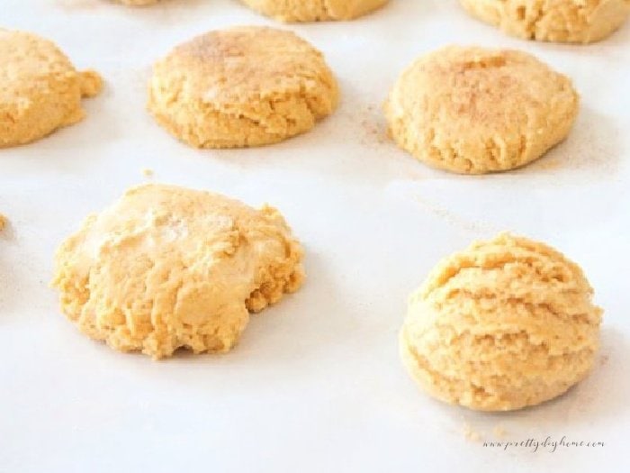 A parchment lined cookie baking sheet covered large scoops of pumpkin spice cookie dough.