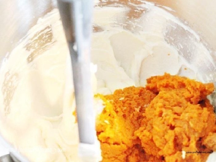 Mixing cream cheese and pumpkin in a large stand mixer with a paddle attachment.