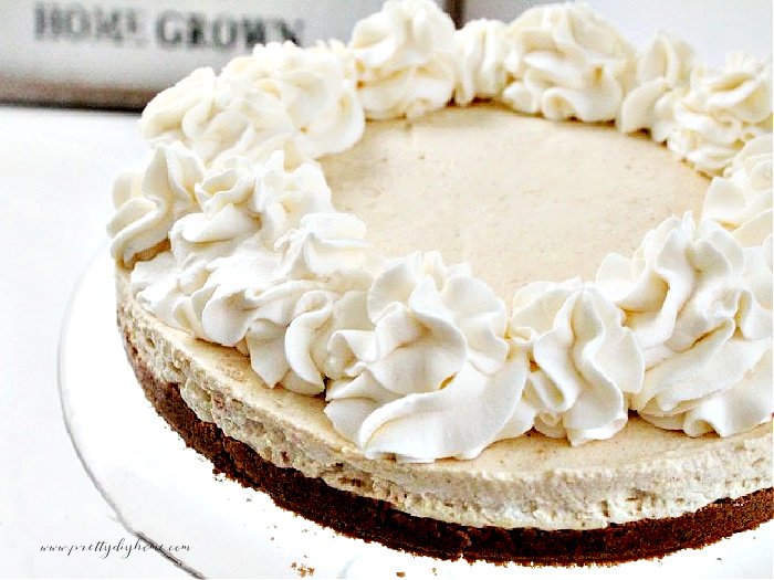 A large homemade pumpkin cheesecake recipe with layers of gingergread crust, pumpkin cream cheese filling and large swirls of whipped cream with cinnamon sugar.