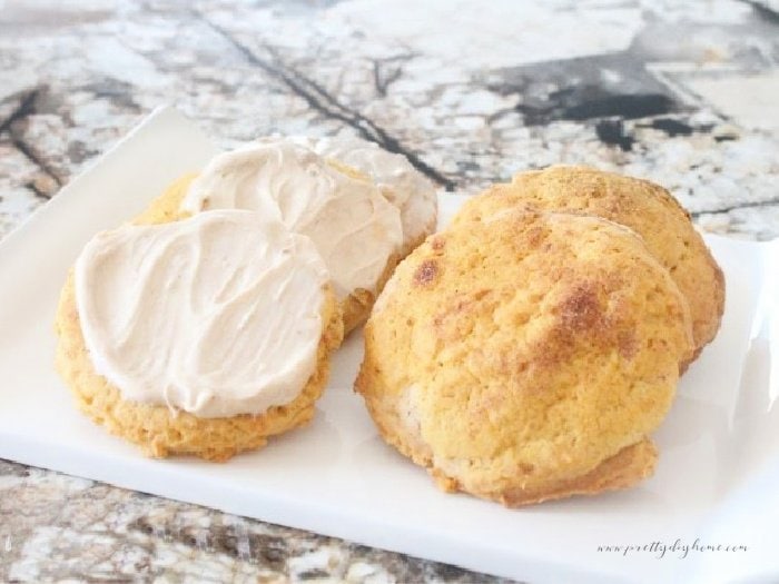 A small tray covered with homemade pumpkin cookies. Half of the large cookies are being served plain with cinnamon sugar crunch on top, the other half have a thick layer of maple flavoured cream cheese icing.