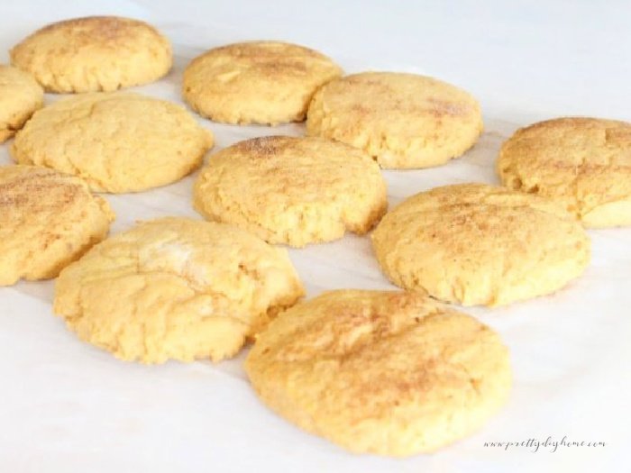 A tray of baked pumpkin cookies lined up on a parchment covered baking sheet.