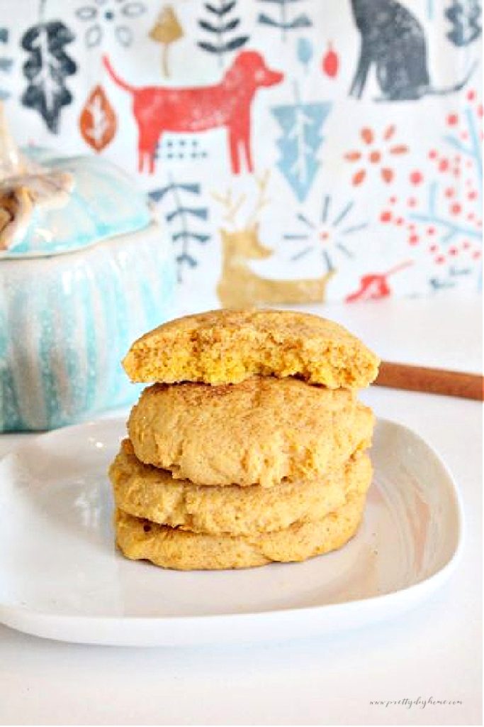 A stack of chewy and soft pumpkin cookies, the top cookie is cut in half to show the soft crumy cake like center of the cookie recipe.