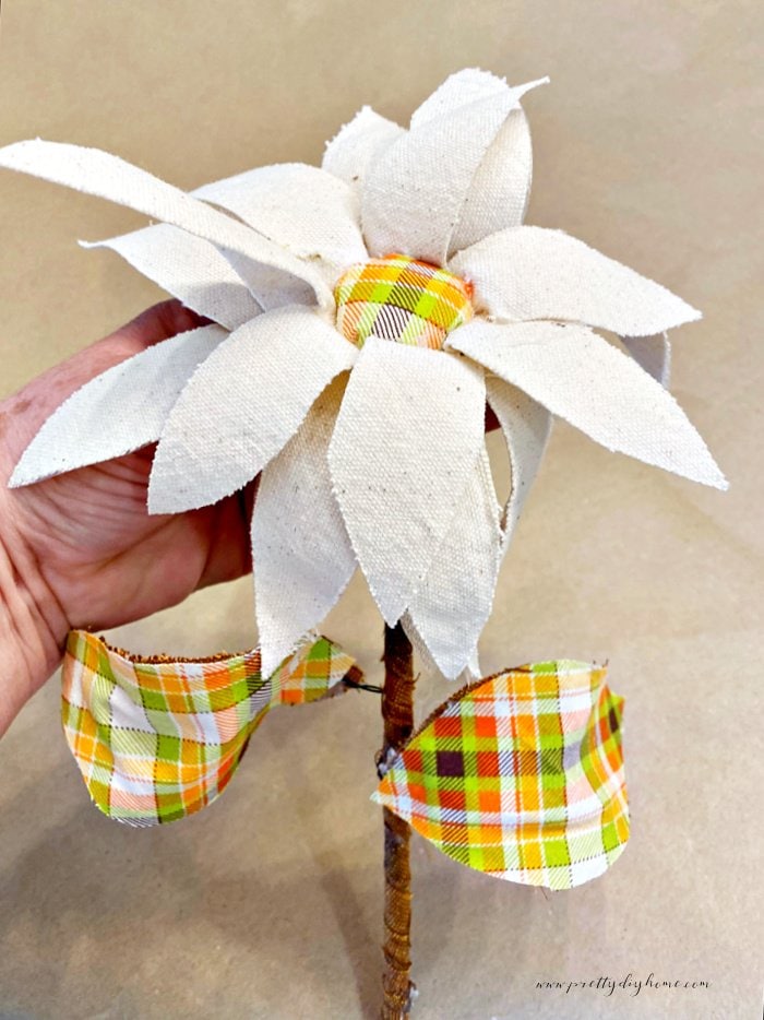 A  DIY fabric flower with cream petals and plaid center and leaves.