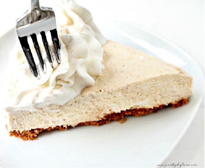 A large slice of no bake pumpkin dessert with whipping cream.  The pumpkin dessert has a fork piercing it.