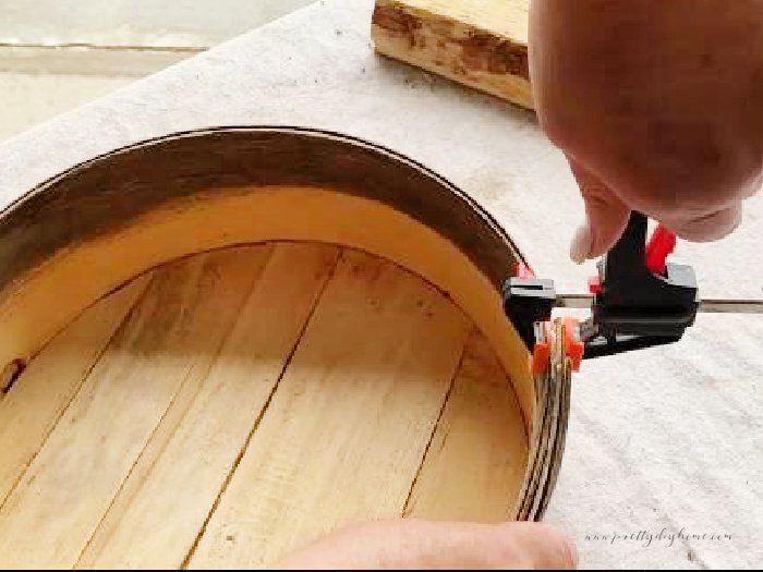 A vintage cheesebox being glued with wood glue and held together with a small wood clamp.