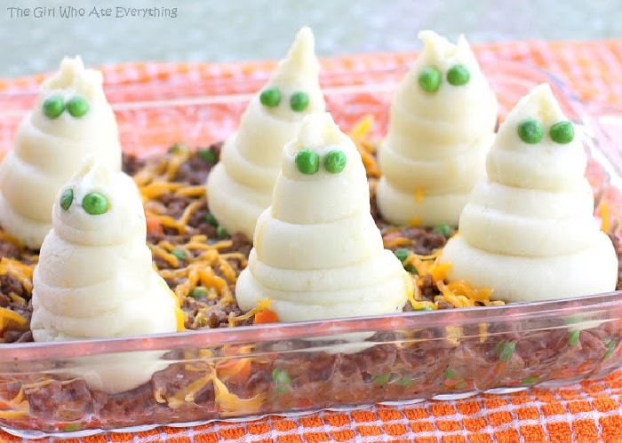 A shepherd pie covered with mounds of ghost shaped potatoes with green pea eyes. An easy Halloween night dinner recipe idea for families.