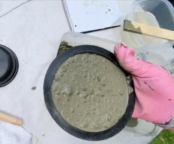 A Dollar Tree plunger head thats been filled with concrete.  Its been flipped over so you can see the concrete inside.  The cement adds weight to the bottom of a DIY Halloween witch broom.