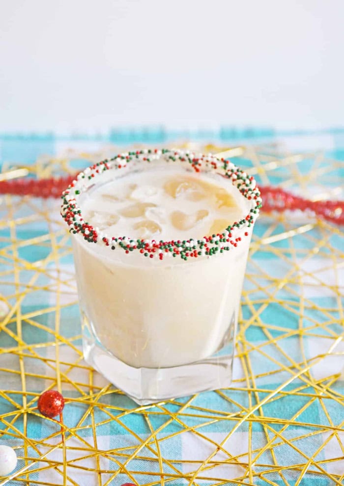 A Christmas cookie cocktail in a short glass rimmed with red white and green sprinkles.  Sweet and delicious baileys Christmas cocktail recipe.