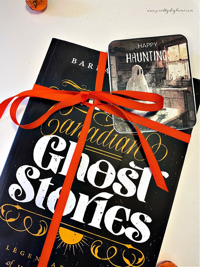 A Happy Hauntings Halloween gift tags tied to a ghost stories book with a pretty orange ribbon.