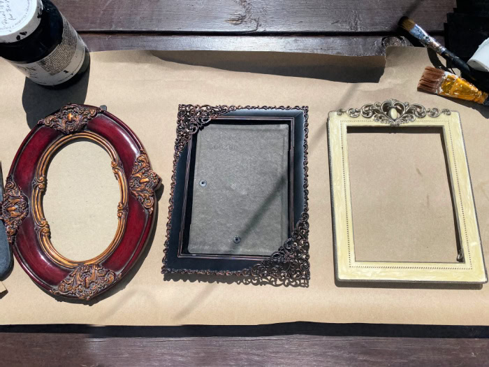 The before picture showing three ornate thrift store frames.  One is red, one is black and one is yellow.  They will be painted to become Halloween frames.