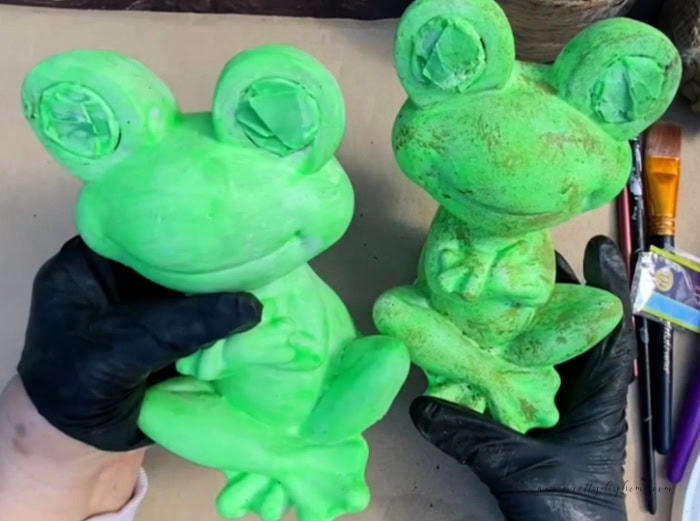 Two handpainted bright neon green frogs being made into DIY Halloween decorations for Outdoors.