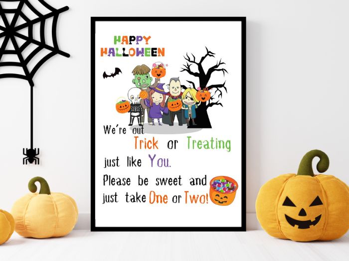 A free printable Halloween candy sign with a group of cartoon people wearing different Halloween costumes. With Happy Halloween written in one corner and a large bowl of candy in the bottom corner.