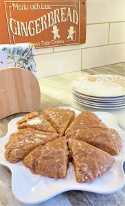 easy to make gingerbread scones sitting on a counter with a small gingerbread cookie jar and vintage gingerbread sign in the background.