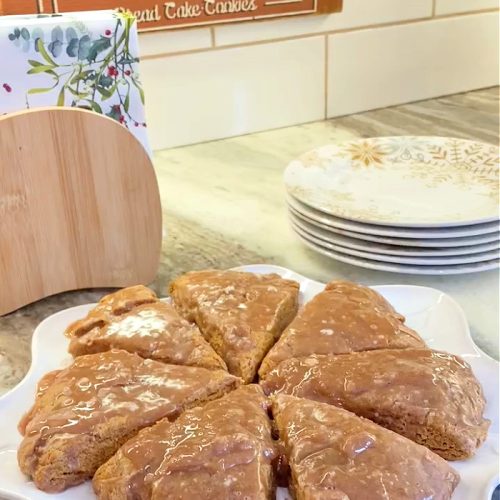 easy to make gingerbread scones sitting on a counter with a small gingerbread cookie jar and vintage gingerbread sign in the background.