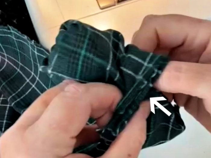 Turning a tube of fabric right side out. There is an arrow showing the direction to push the fabric.