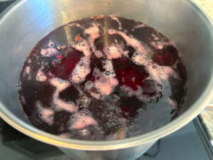 A large stainless steel pot filled with beets being cooked for homemade beet relish.