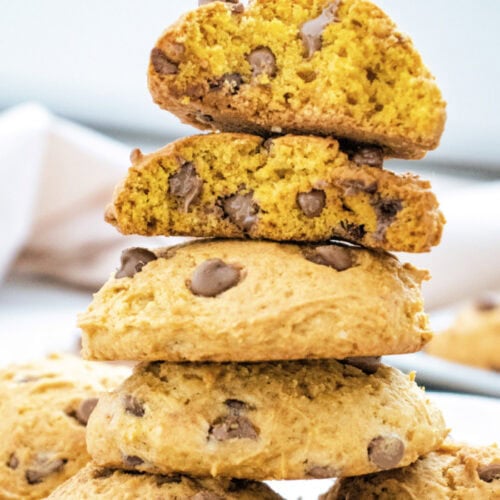 A large stack of golden brown pumpkin cookies. These pumpkin cookies can have chocolate chips or white chocolate chips added.