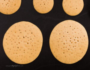 A pancake griddle covered with large and small pumpkin pancakes. You can see they are ready to turn over because of little dots in the batter.