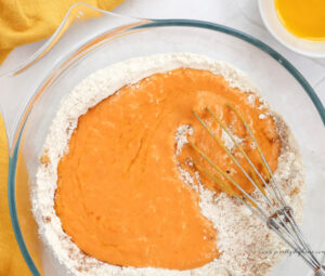 Mixing wet pumpkin pancake ingredients into the dry ingredients with a whisk. An easy pumpkin pancake recipe with only two bowls.