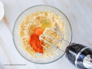 A large bowl sitting on a marble counter. The bowl is filled with the wet ingredients for a pumpkin cookie recipe.
