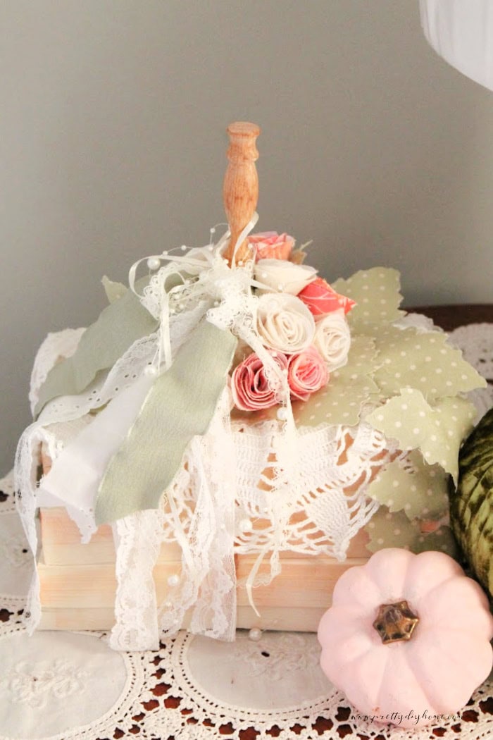 A Pumpkin projects in a vintage style with feminine fabric roses, lots of lace, in soft pinks and creams. The pumpkin is made using a bookstack for a gorgeous feminine neutral fall pumpkin craft..