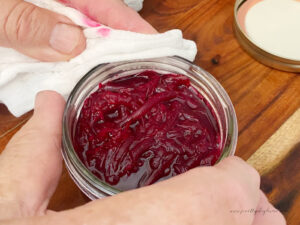 wiping the rim of a jar with a clean cloth prior to placing a lid and the ring on it.