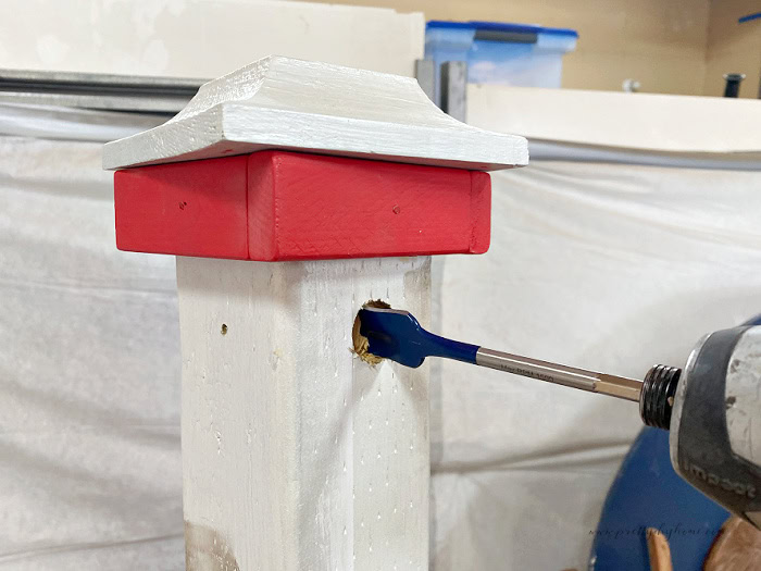 Drilling a hole in a 4x4 post for the spindle on a DIY outdoor Halloween sign.