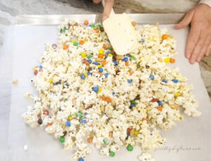 A cookie sheet covered with a slab of homemade Halloween popcorn being pressed into shape with a spatula.
