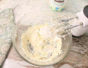Mixing sour cream into well beaten butter using an electric mixer. The first step to making a pumpkin loaf recipe with sour cream.