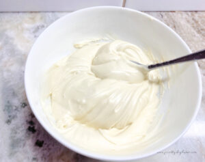 A white bowl filled with melted white chocolate that is smooth.