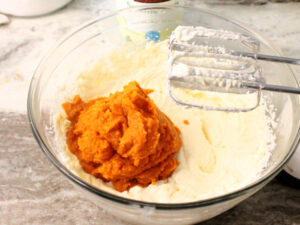 The wet ingredients for a pumpkin loaf recipe, their is a 2 cup portion of pumpkin puree being added to the bowl.