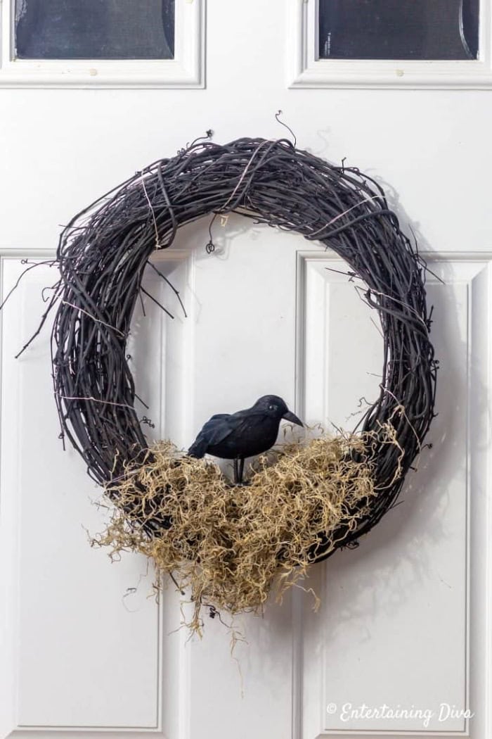 An easy black Halloween wreath with Spanish moss, a faux crow, and twinkle lights.