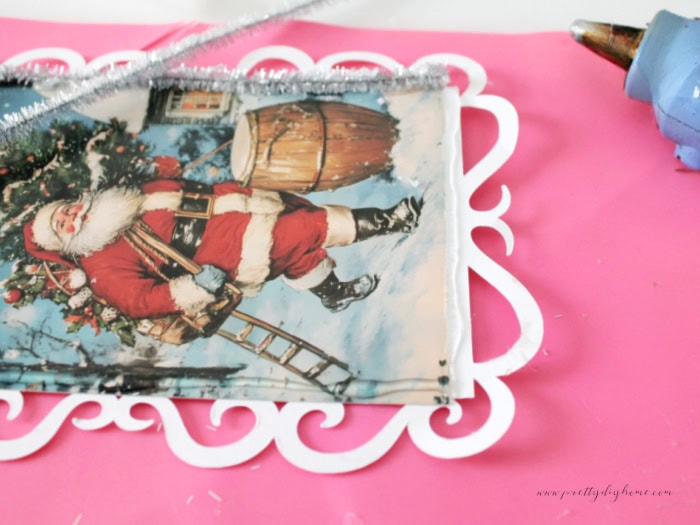 Attaching silver tinsel edging to the postcard panel with a line of hot glue.