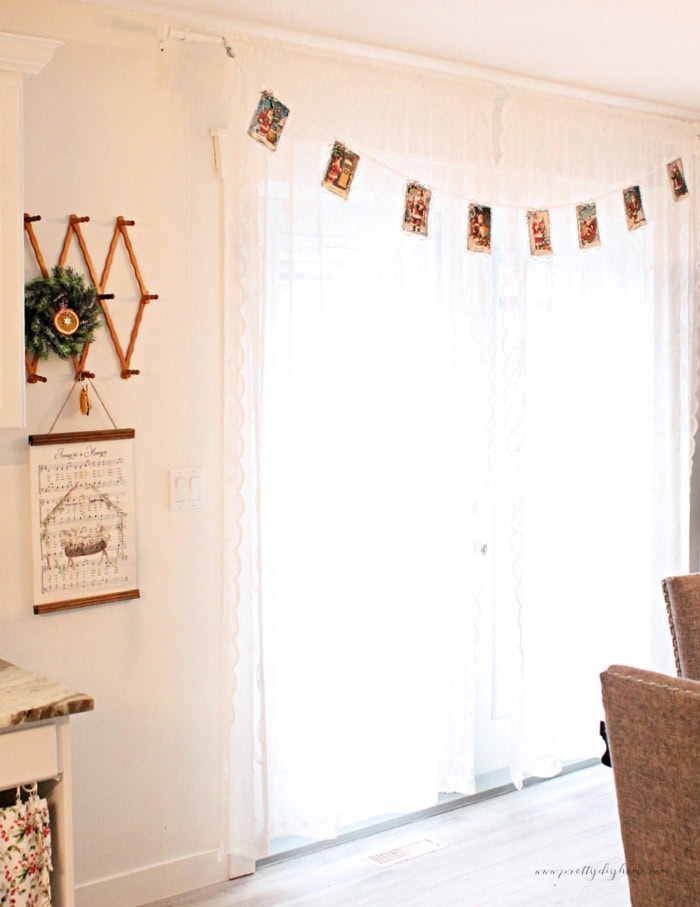 Full length vintage Santa banner hanging across a lace-curtained dining room window.