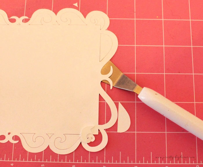 Using a Cricut spatula to lift small pieces while weeding the lace background for a Santa banner.