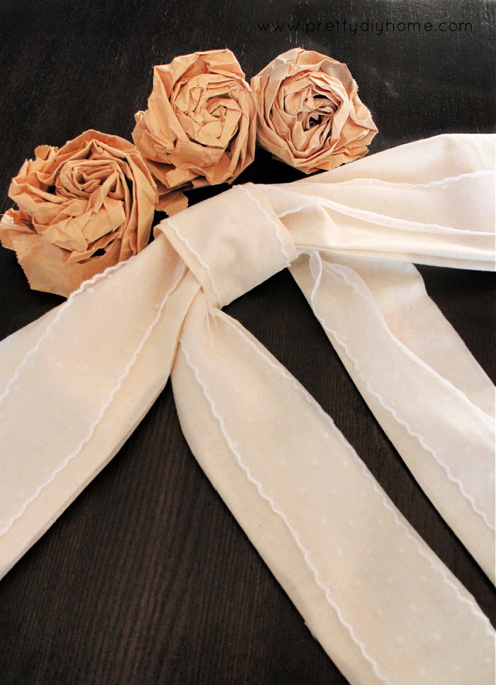 Finished large romantic fabric bow made from muslin and lace and styles with paper bag roses.