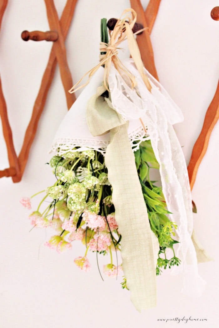 Hanging vintage doily flower bundle with lace wrap, ribbon, and raffia details