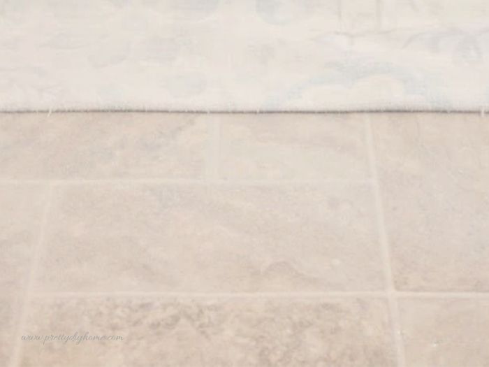 A DIY pet feeding mat showing spray adhesive applied to linoleum before attaching the fabric.