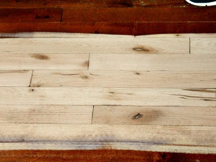 Hardwood floor after first sanding pass showing raw wood.