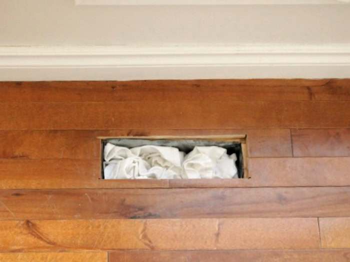The hardwood floor with open vent removed before refinishing.