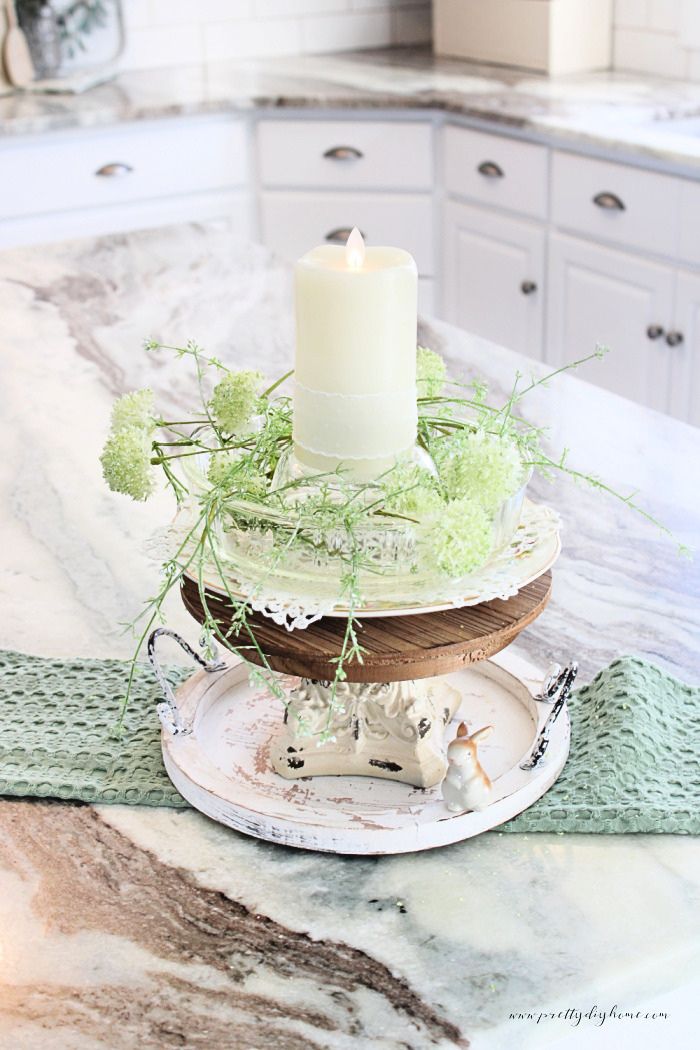 A vintage glass bundt pan used to create a kitchen table centerpiece with soft greenery and layered decor.