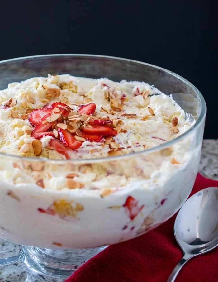 Easy potluck punch bowl cake layered with berries, cake, pudding, and whipped topping.