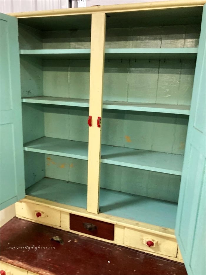 Original turquoise green interior inside an antique kitchen cabinet before repainting and vintage cabinet makeover.
