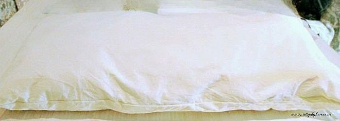 Simple DIY pillow insert made from fabric and filled to fit a bench cushion back.