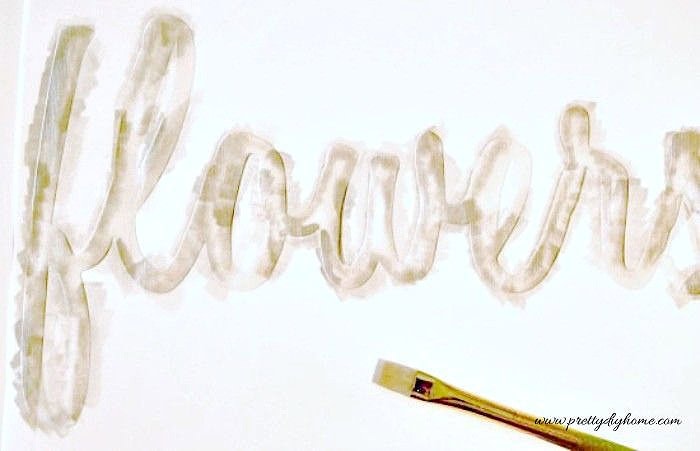 Painting letters onto fabric using a stencil for a DIY cushion cover.