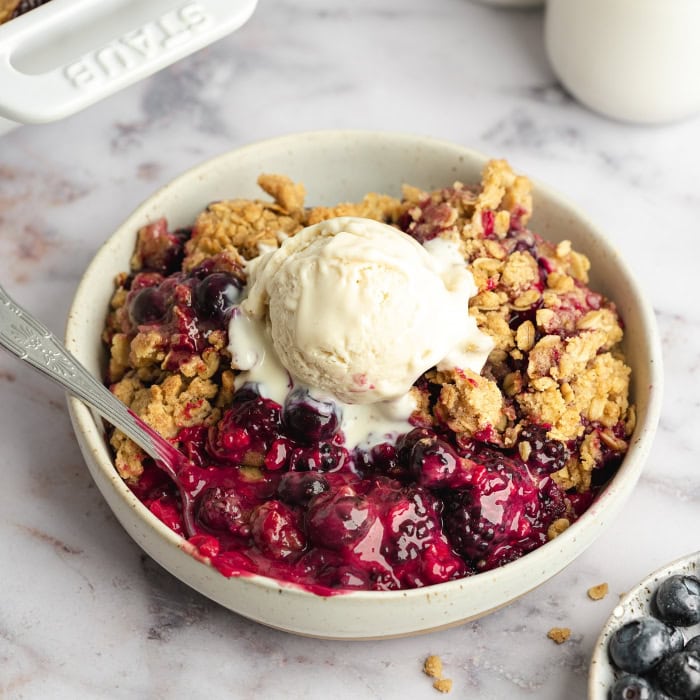 Easy vegan triple berry crisp served with vanilla ice cream.